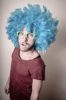 hipster stylish funny man with blue wig on gray background