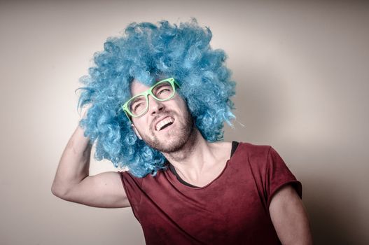 hipster stylish funny man with blue wig on gray background