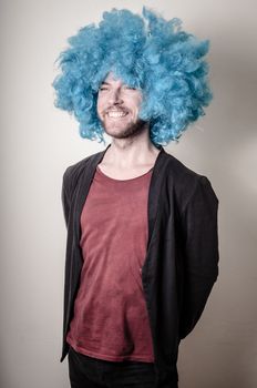 hipster stylish funny man with blue wig on gray background