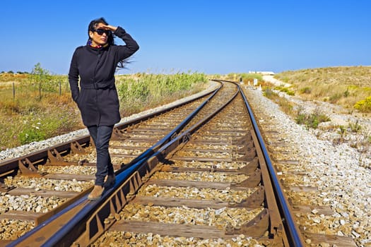 Woman looking for the train at a railroad track