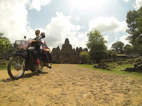 ANGKOR, CAMBODIA - June 03: Two Khmer girls on motorbike coming out of Bayon temple in Angkor Thom Cambodia on June 3rd 2013. Bayon temple  was built late 12th century by Jayavarman VII