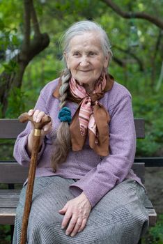 old grandmother with a long braid in the summer in the garden