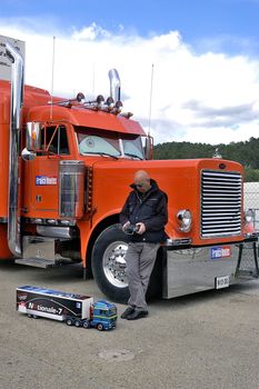 lorry driver having fun with a small truck radiocontrolled in front of its enormous truck