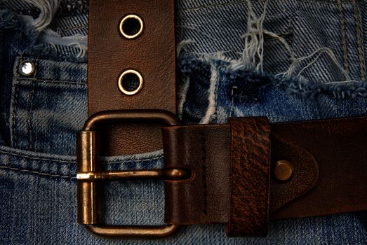 Close-up photo of the brown belt on old blue jeans