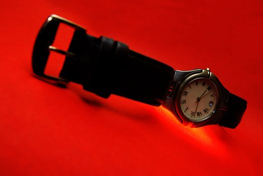 Silver watch with leather bracelet on a red background