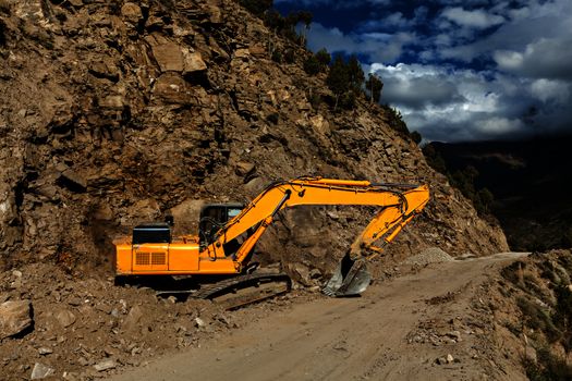 Road construction in mountains Himalayas - excavator. Lahaul valley, Himachal Pradesh, India