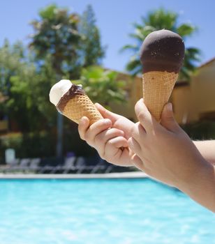 Ice cream in a child's hand close-up on the background of the swimming pool