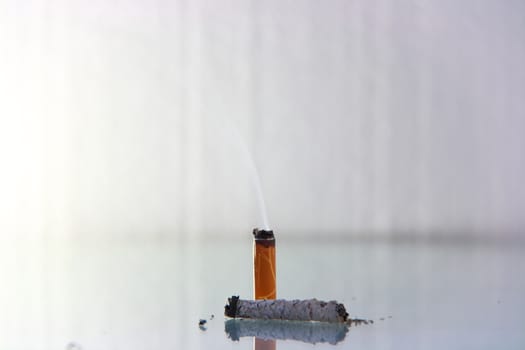 hand made cigarette burning in front of white background