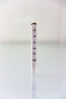 hand made cigarette burning in front of white background