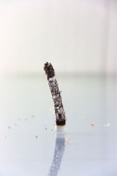 hand made cigarette burning in front of white background