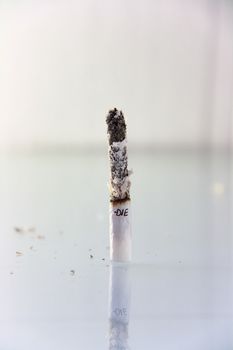 hand made cigarette burning in front of white background