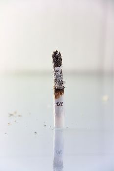 hand made cigarette burning in front of white background