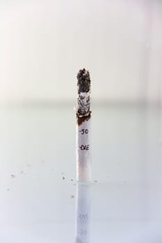 hand made cigarette burning in front of white background