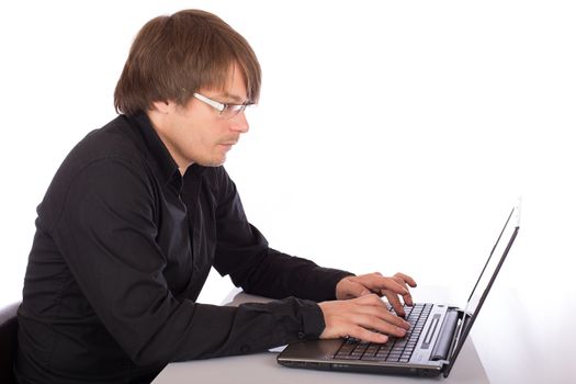 Concentrated young man with black shirt working seriously on a laptop. Isolated on white background.