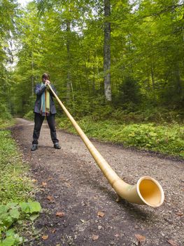 NEUCHATEL, SWITZERLAND - SEPTEMBER 18: Swiss musician playing his typical Alphorn for a group of hikers while hiking to the summit of Creux du Van on September 18, 2010 in Neuchatel, Switzerland 