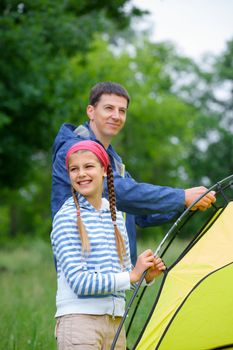 Young girl with her father near tent in camping on the nature