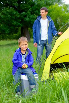 Young boy with his father near tent in camping on the nature