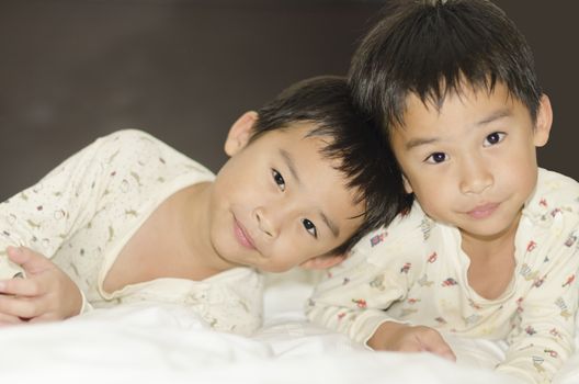 two twins brothers lying on bed