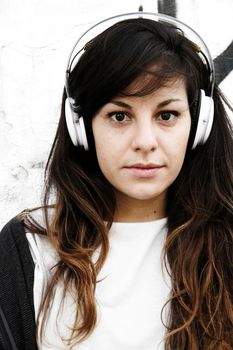 Girl listening to Music while leaning on a Wall.