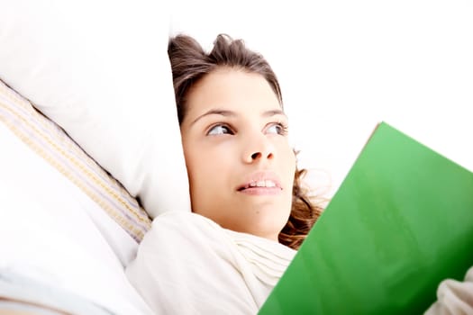 A young latin woman reading a book in bed.