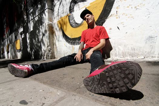 A Rapper leaning against a Graffiti wall.