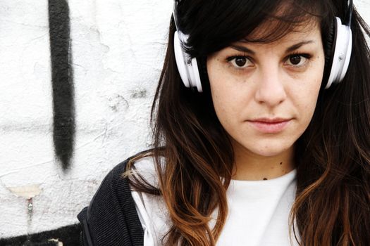 Girl listening to Music while leaning on a Wall.