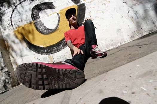 A Rapper leaning against a Graffiti wall.