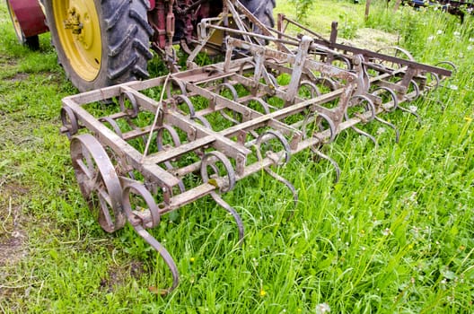 tractor on farm field gras with old metal harrow