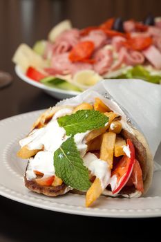 Traditional Gyro sandwich with meat  tzatziki sauce tomato onions and fried potato garnished with mint. Shallow depth of field.