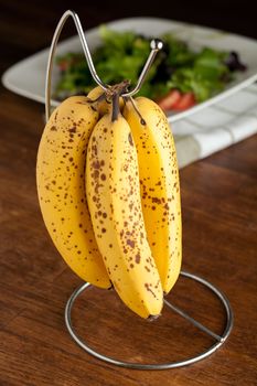 Spotted bananas that are sweet and ripened hanging on a rack.