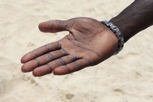  Open hand of the black man on a background of sand