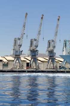 Row of cranes and their reflections in the sea in Eilat harbor, Israel