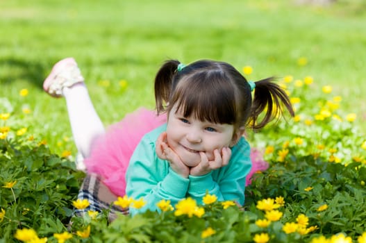 little girl lies on a glade with dandelions