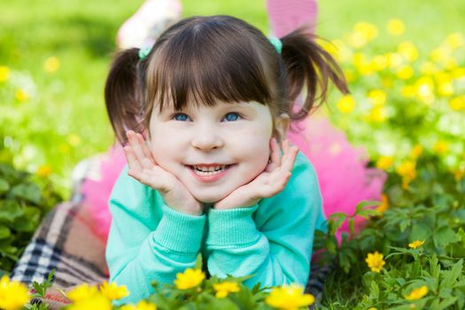 Portrait of the child lying on a grass with dandelions