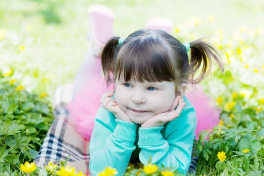 Portrait of the girl lying on a glade with dandelions