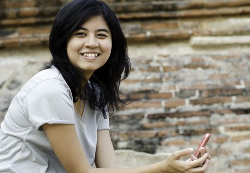 Smiling woman holds her phone with brick background