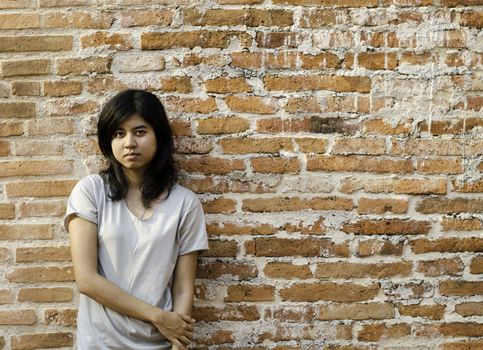 Young Asian woman against a Brick Wall with Copy Space. 