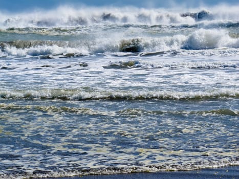 Background texture pattern of waves breaking and rolling onto beach on a sunny day