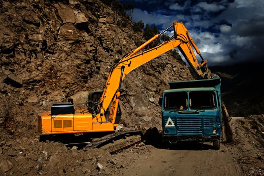 Road construction in mountains Himalayas - excavator and truck.  Lahaul valley, Himachal Pradesh, India