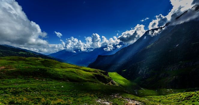 Peaceful alpine meadow mountain panorama in Himalayas with sun rays
