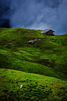 Serenity serene lonely scenery background concept - house in hills in mountins on alpine meadow in clouds