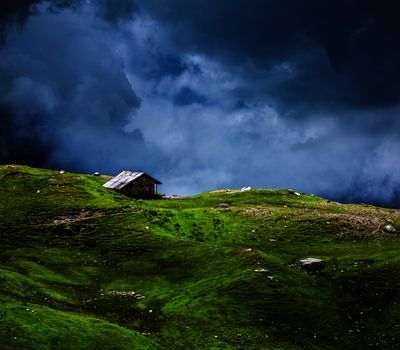 Serenity serene lonely scenery background concept - house in hills in mountins on alpine meadow in clouds