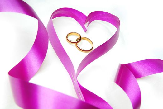 Wedding rings in the purple ribbon in the shape of heart