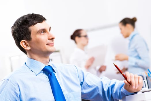 Portrait of a businessman in a blue shirt in the background of colleagues discussing