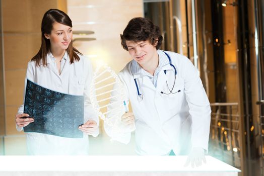 two doctors stand near glowing table discussing. projected objects on a desk