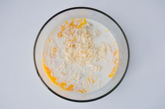 Mix of Raw eggs and milk in glass bowl.