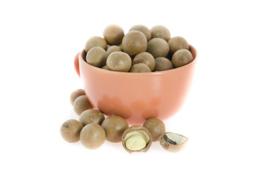 Shelled and unshelled macadamia nuts  in a cup on white background