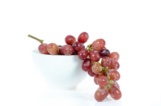 A bunch of red grapes in a white bowl 