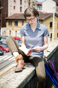 young beautiful hipster woman reading book in the city