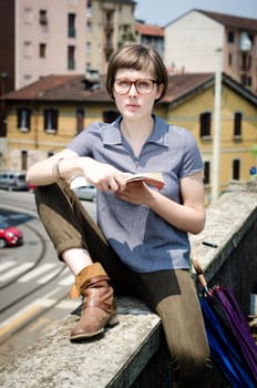 young beautiful hipster woman reading book in the city